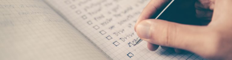 person writing checklist in notebook, what to look for in a psychedelic therapist