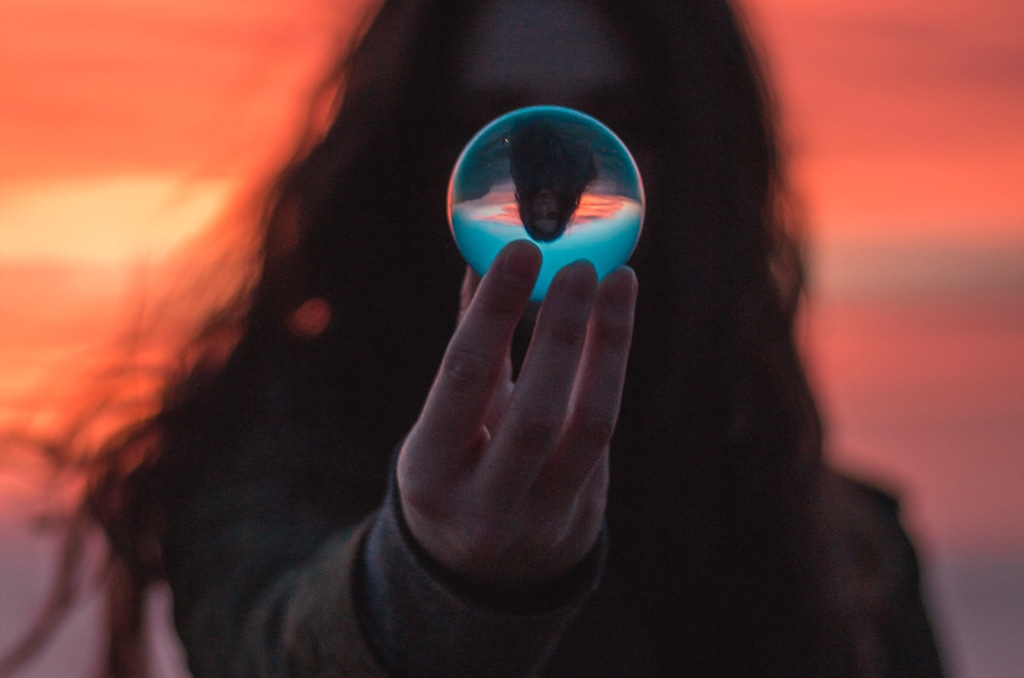 woman looking through glass orb at sunset, psychedelics and the mind