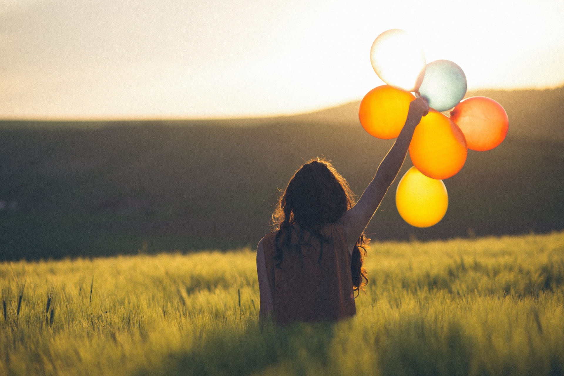 woman holding balloons in a field